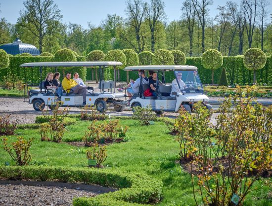 Tūristu grupa bauda izbraucienu ar elektromobili pa Rundāles pils parku. 