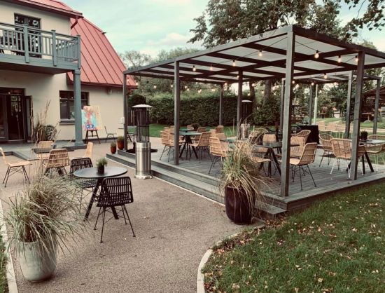 Gai&scaron;a un pla&scaron;a restorāna 'Rezidence' āra terase ar koka mēbelēm.