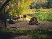 Privāta atpūtas zona dārzā pie 'Rundāles namiņa' ar koka galdu un grila vietu. Iežogota teritorija, kas nodro&scaron;ina diskrētu atpūtu dabā, pie ūdenstilpnes. 