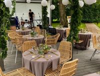 Restorāna 'Rezidence' terase, kas sagatavota dzīvās mūzikas koncertam: skaisti klāti galdi ar auduma galdautiem, un apzeltītiem  galda piederumiem, radot svinīgu noskaņu īpa&scaron;iem dzīves notikumiem.