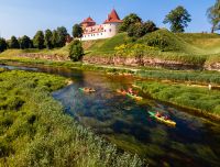 Brāļu laivas ar laivotājiem uz Bauskas pils fona