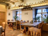 Viesu namsa Baltā māja kafejnīcas iekārtojums -  vienkār&scaron;s interjers, kurā dominē  koks., ķieģeļu grīda